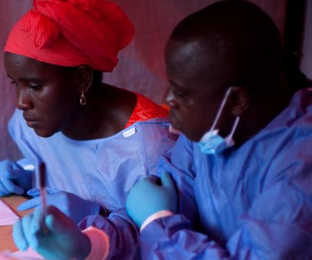 Nene Aminata Diallo and Gamou Saiman Gaston, from the WHO Ebola vaccination team, carefully go through the consent process with a participant in the Ebola vaccine trial. Obtaining clear consent from participants, that this is a trial, that there are no guarantees, that there may be unexpected consequences from the vaccine, is important in the trial process.